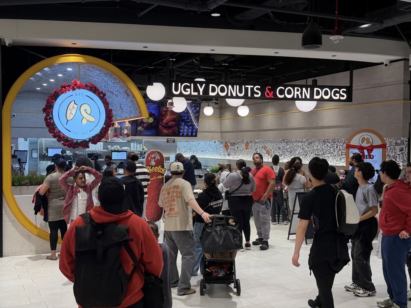 An Ugly Donuts store in a busy mall, customers lined up